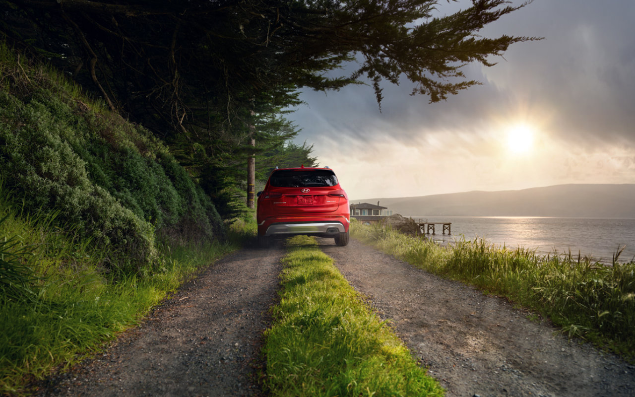 vue arrière d'un Hyundai Santa Fe 2023 sur une route longeant un lac au crépuscule